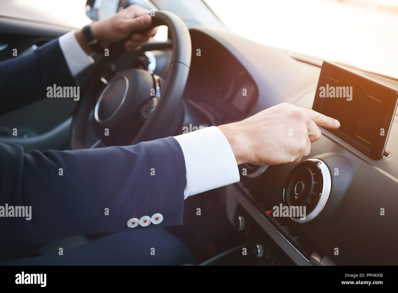 Close-up di un man mano toccando lo schermo nero smartphone su un dashboard. Foto Stock
