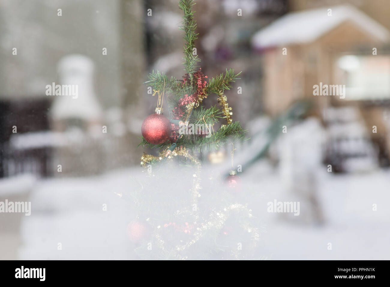 Vacanze Inverno stagione concetto con albero di Natale decorato fotografato attraverso una finestra nella quale nevoso inverno la natura è riflettente. Foto Stock