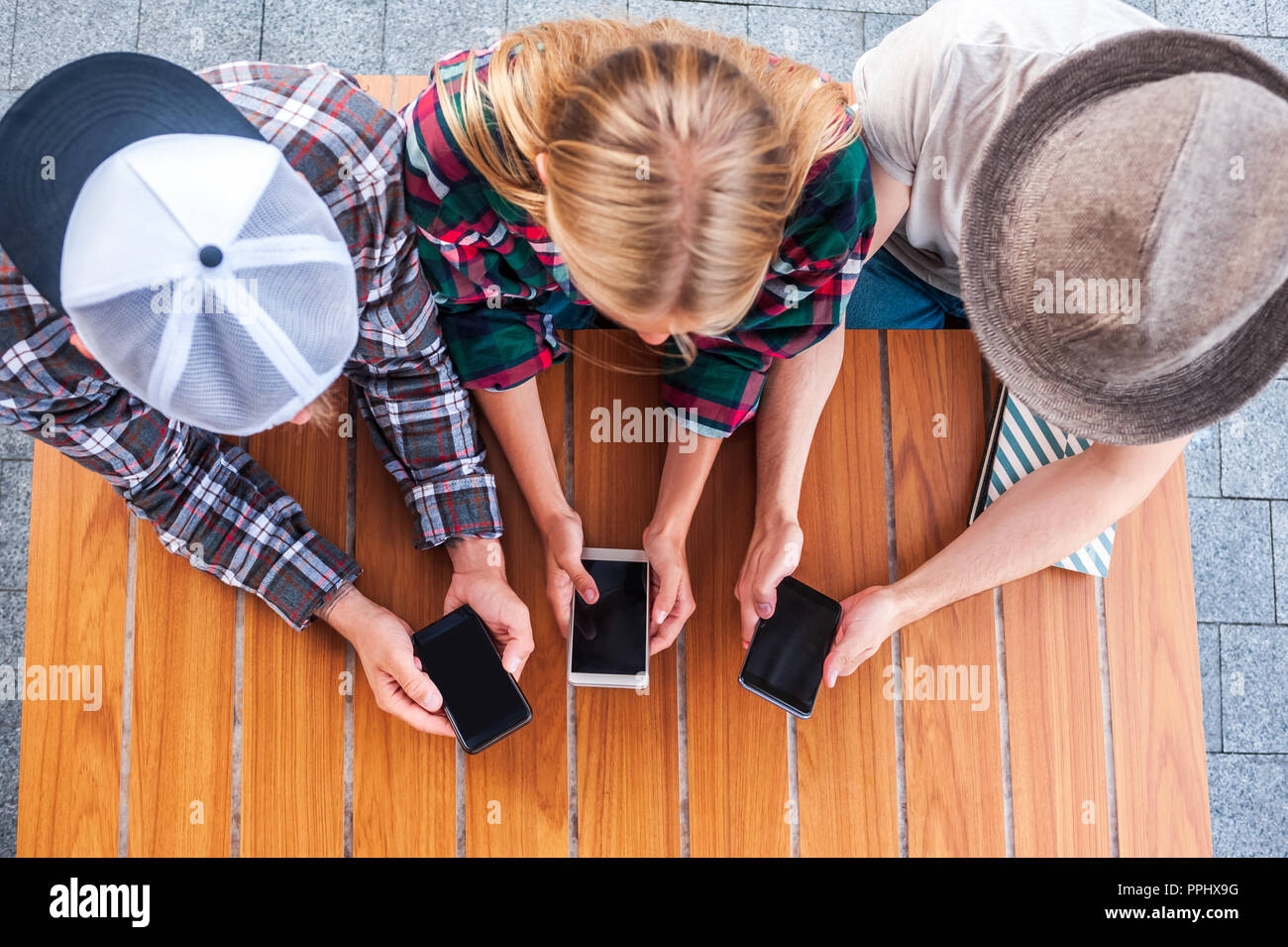 Vista aerea di giovani amici utilizzando gli smartphone con schermi vuoti al tavolo di legno Foto Stock