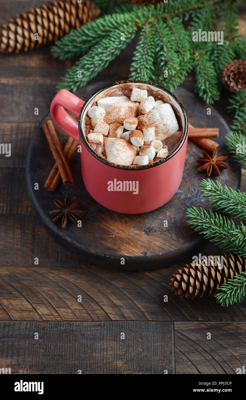 Cioccolata calda con marshmallows su legno rustico sfondo. Concetto di Natale decorato con rami di abete e coni. Foto Stock