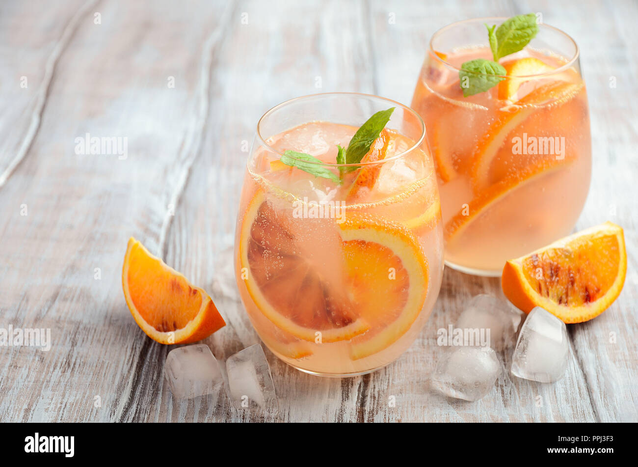 Cold drink rinfrescante con sangue fettine di arancia in un bicchiere su un sfondo di legno. Foto Stock