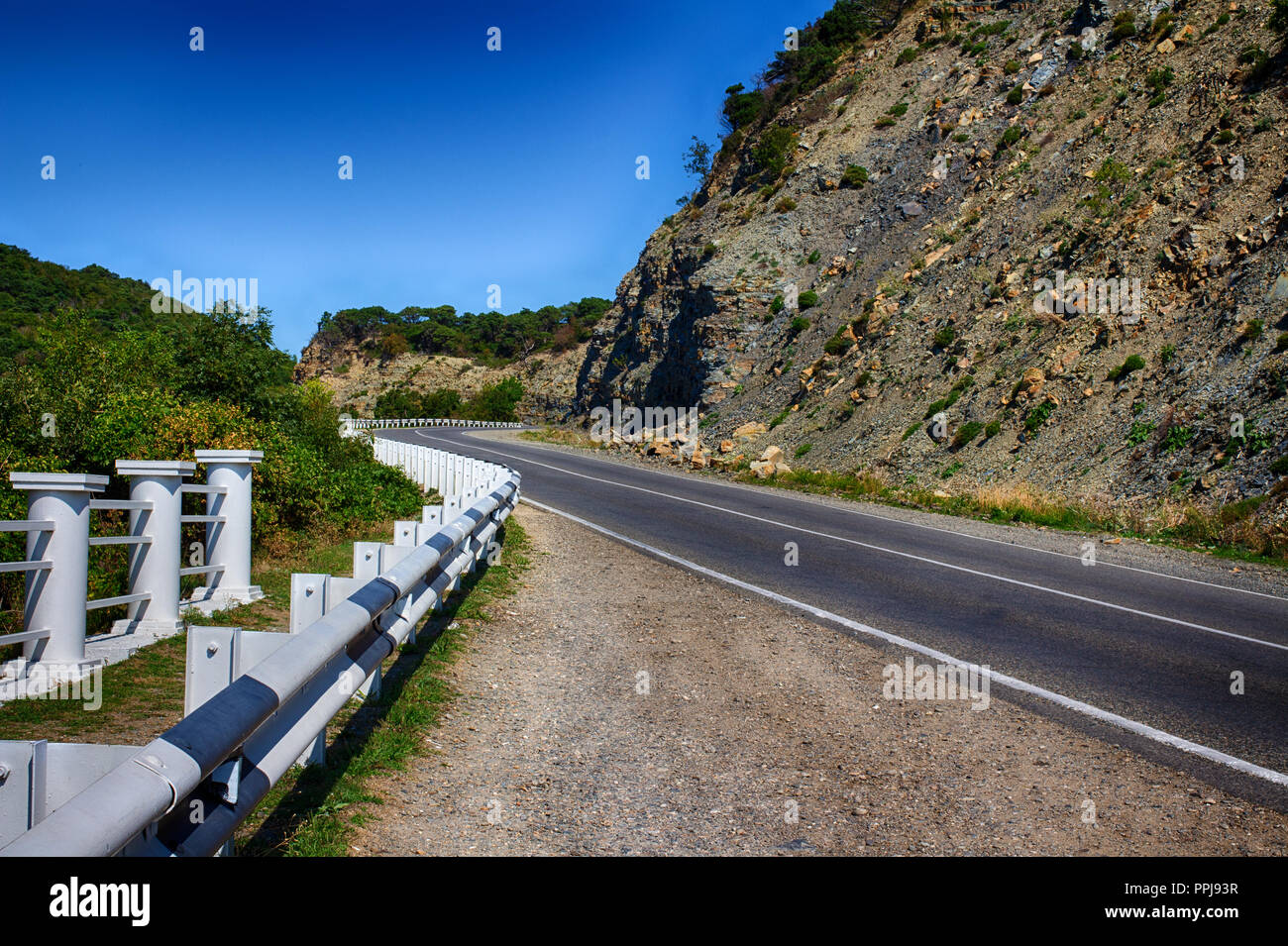 La prospettiva di una strada di montagna, una svolta pericolosa. Paesaggio estivo. La strada è in vacanza. Foto Stock