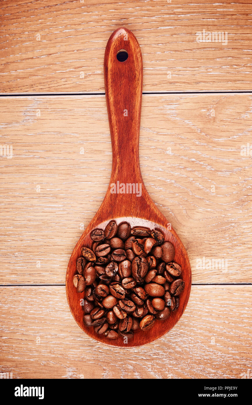 Il cucchiaio di legno con i chicchi di caffè sul tavolo Foto Stock