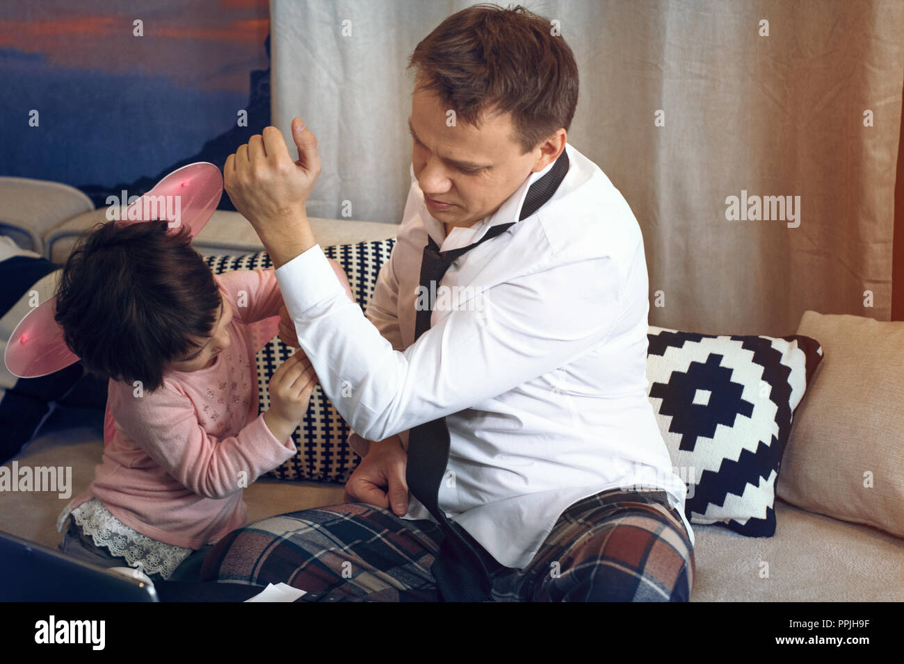 Figlia aiutando padre pulsante shirt Foto Stock