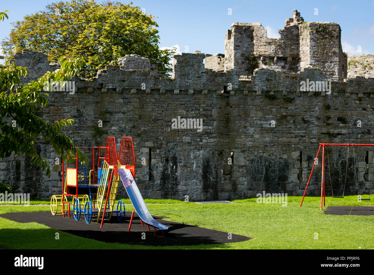 Beaumaris Castle in Beaumaris con altalena per bambini parco di fronte. Anglesey, Galles del Nord Foto Stock