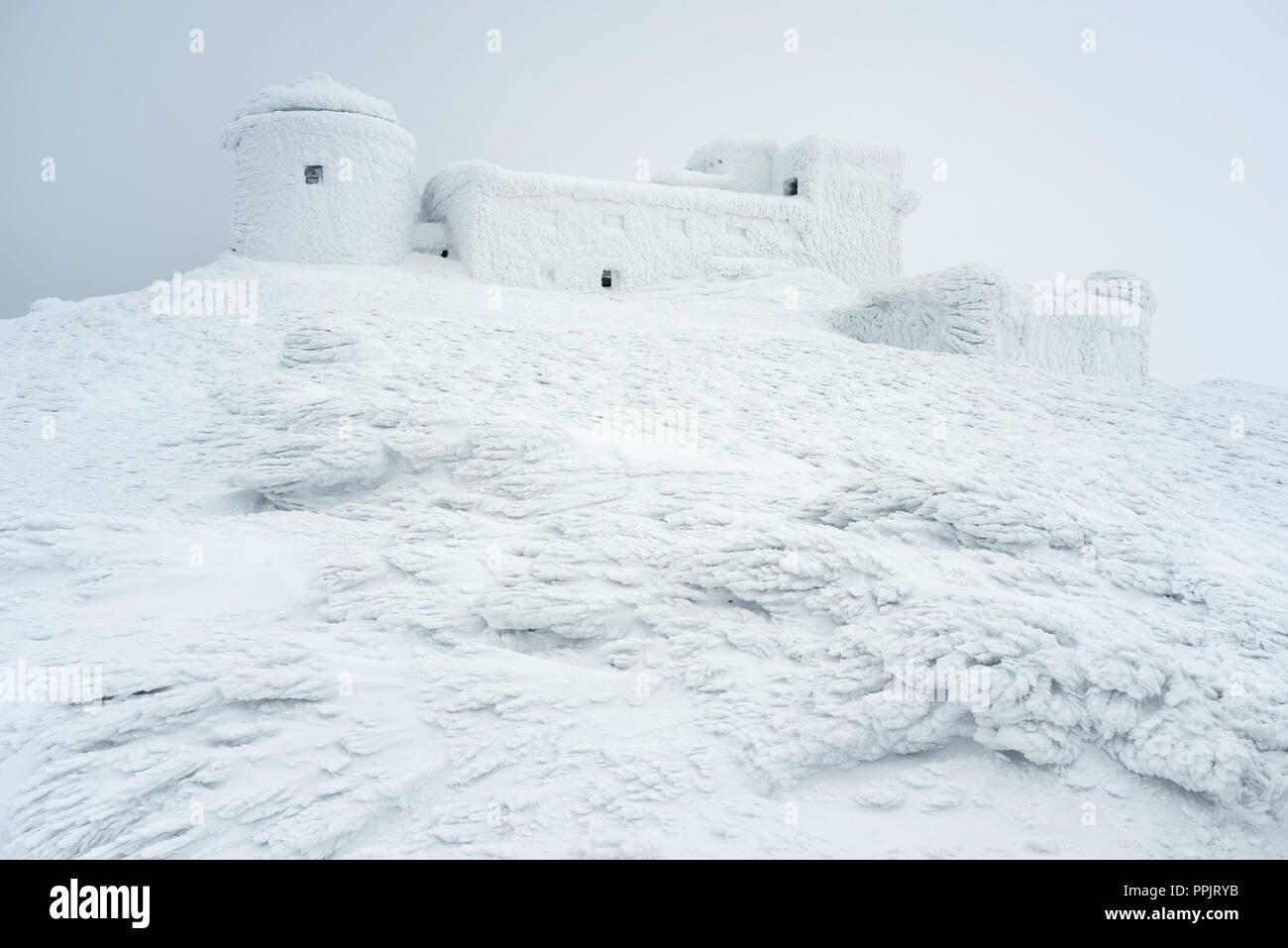 Paesaggio invernale con una bella texture della neve. Il vecchio osservatorio sulla cima della montagna. Giorno nuvoloso. Carpazi, Ucraina, Europa Foto Stock