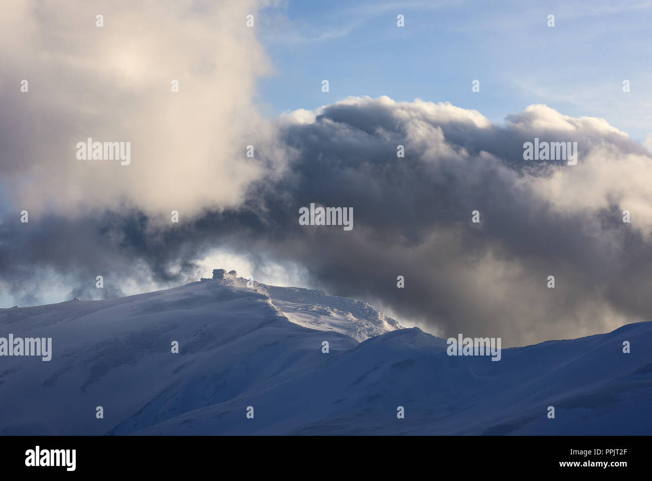 Paesaggio invernale con il vecchio osservatorio sulla cima della montagna. Sky con belle nubi in serata la luce del sole. Carpazi, Ucraina, Europa Foto Stock