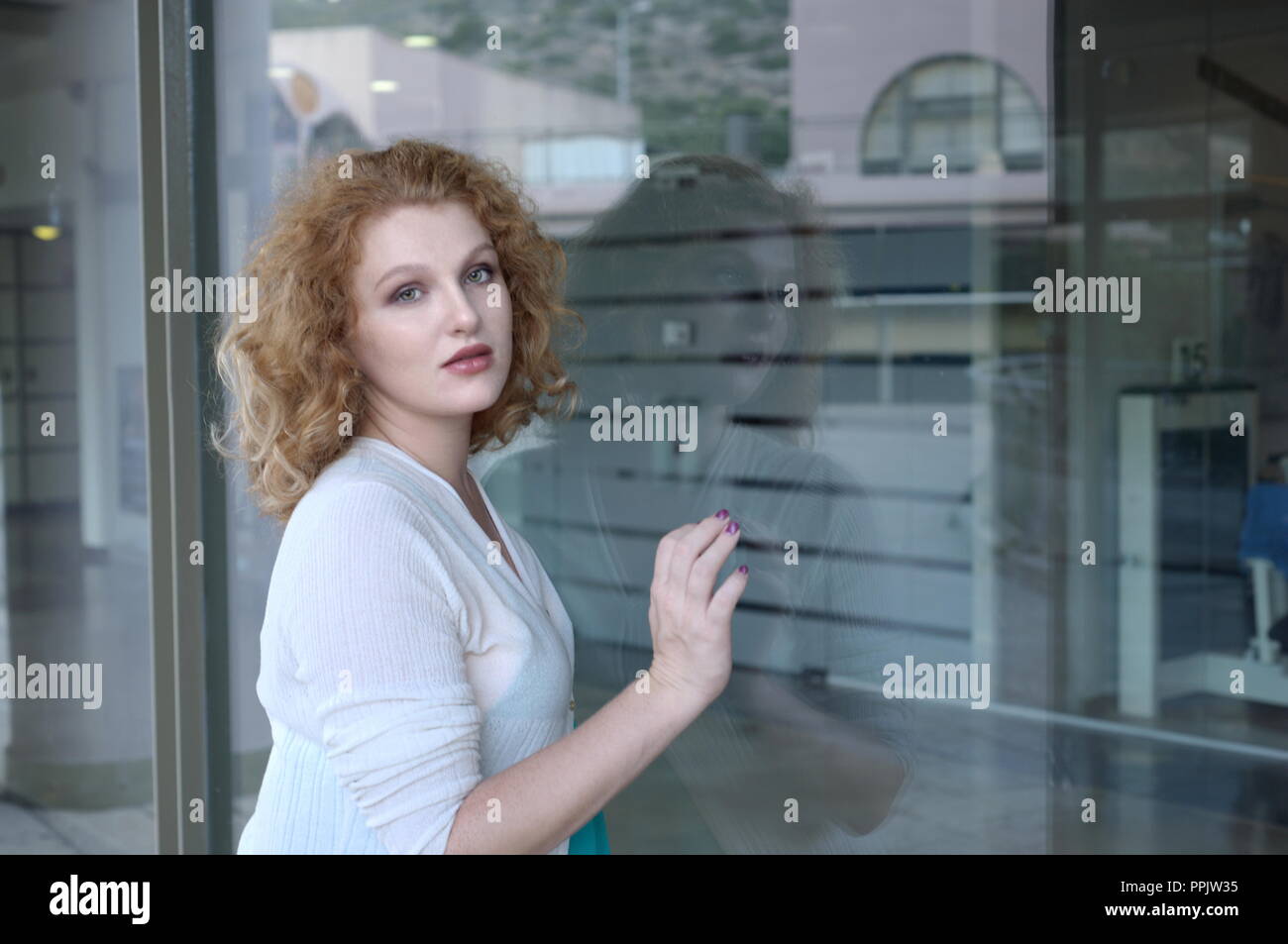 Donna contro la finestra di vetro Foto Stock