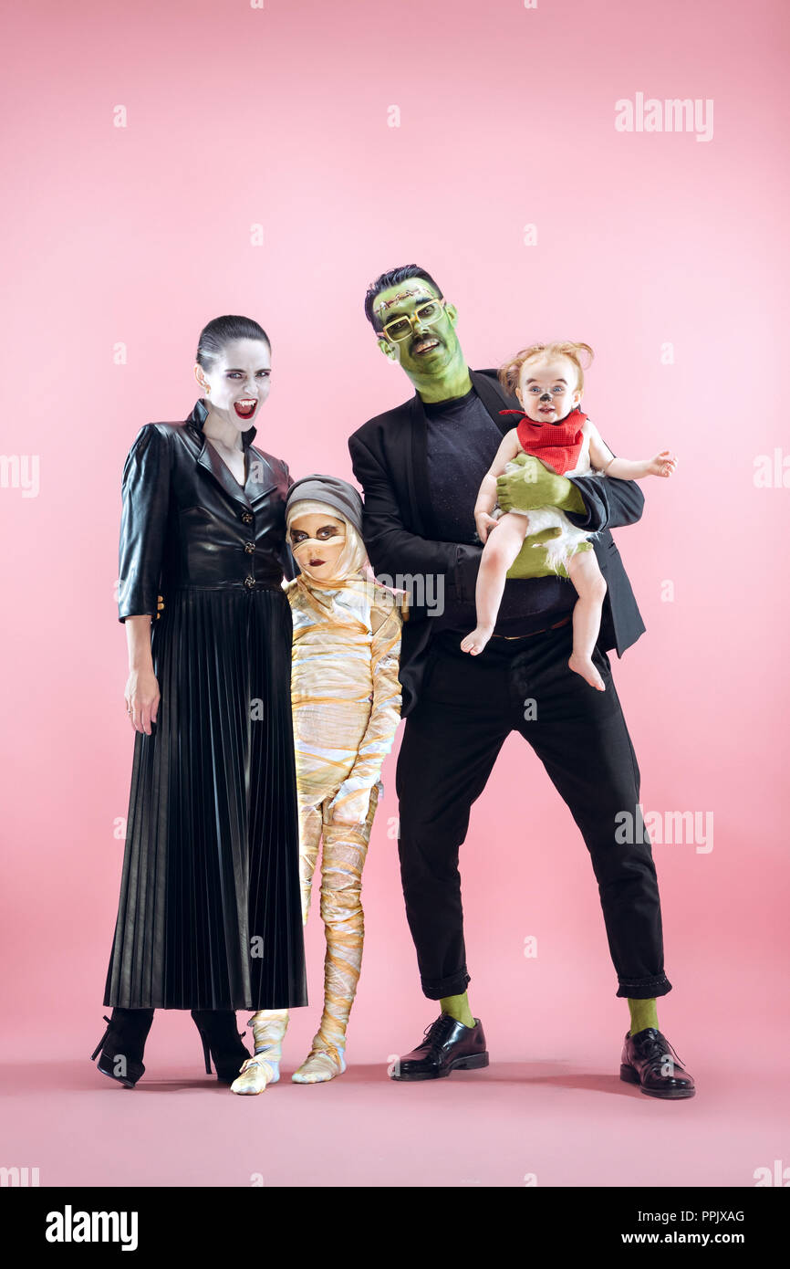 Famiglia di Halloween. Felice padre, madre e figli ragazze in Costume di Halloween e il trucco. Bloody tema: crazy maniak volti sul rosa di sfondo per studio Foto Stock