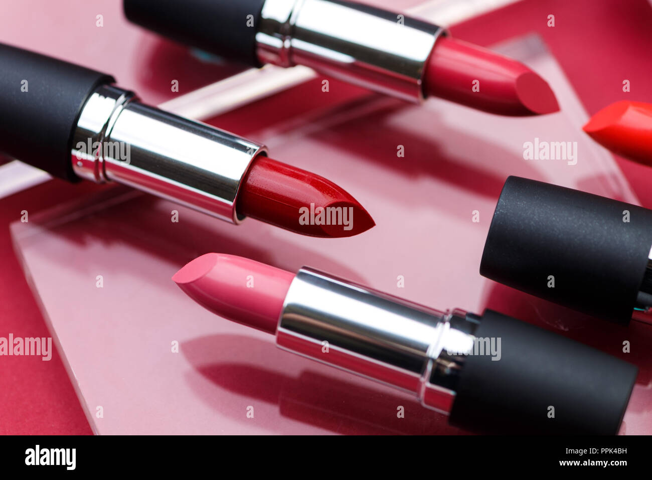 Close up studio shot concettuale / cosmetici prodotto di bellezza - rosso e rosa rossetti Foto Stock