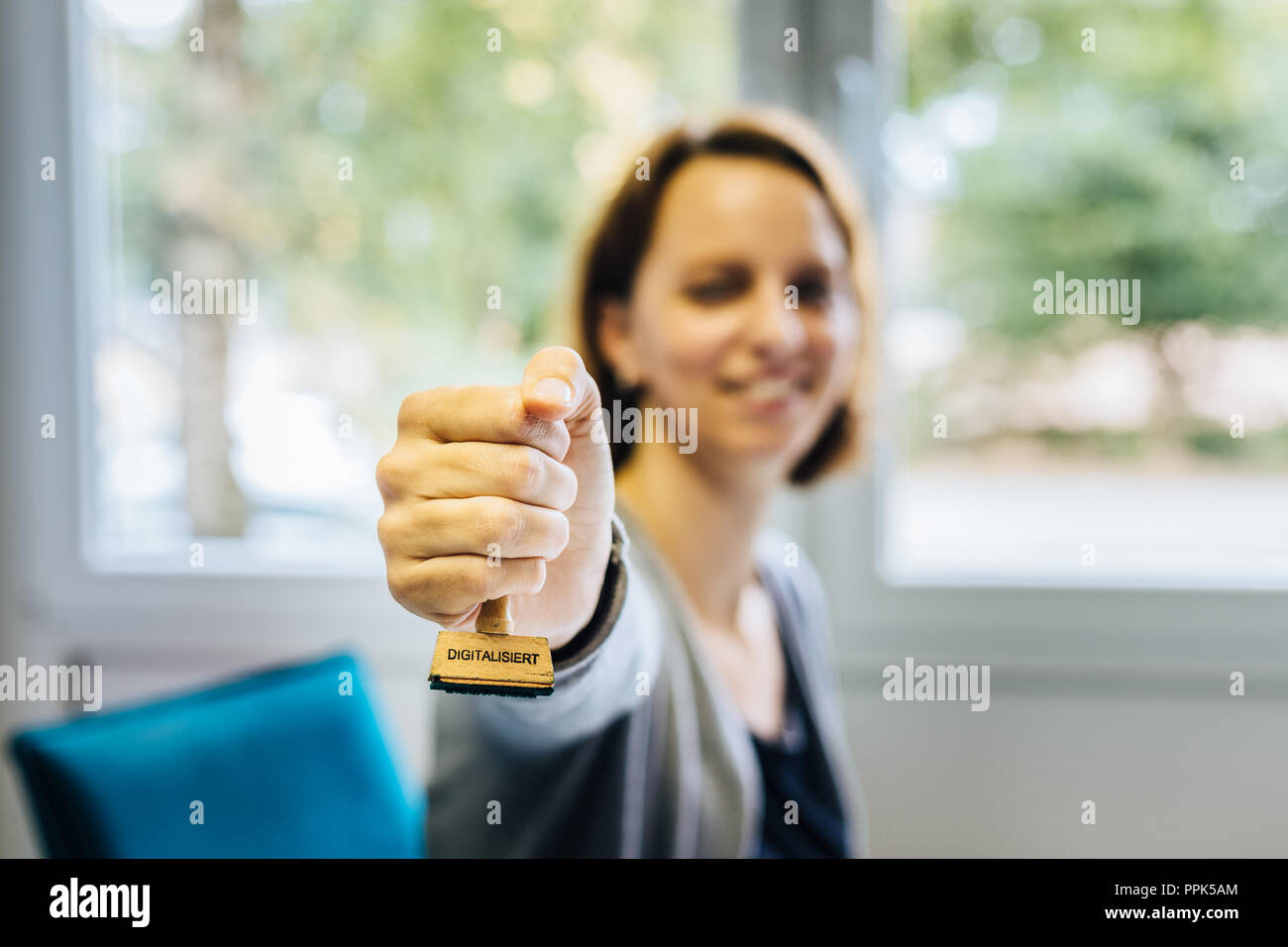 Una donna in un ufficio detiene un francobollo di legno con la parola tedesca "igitalisiert' che significa 'igitalized' nella fotocamera, la profondità di campo Foto Stock