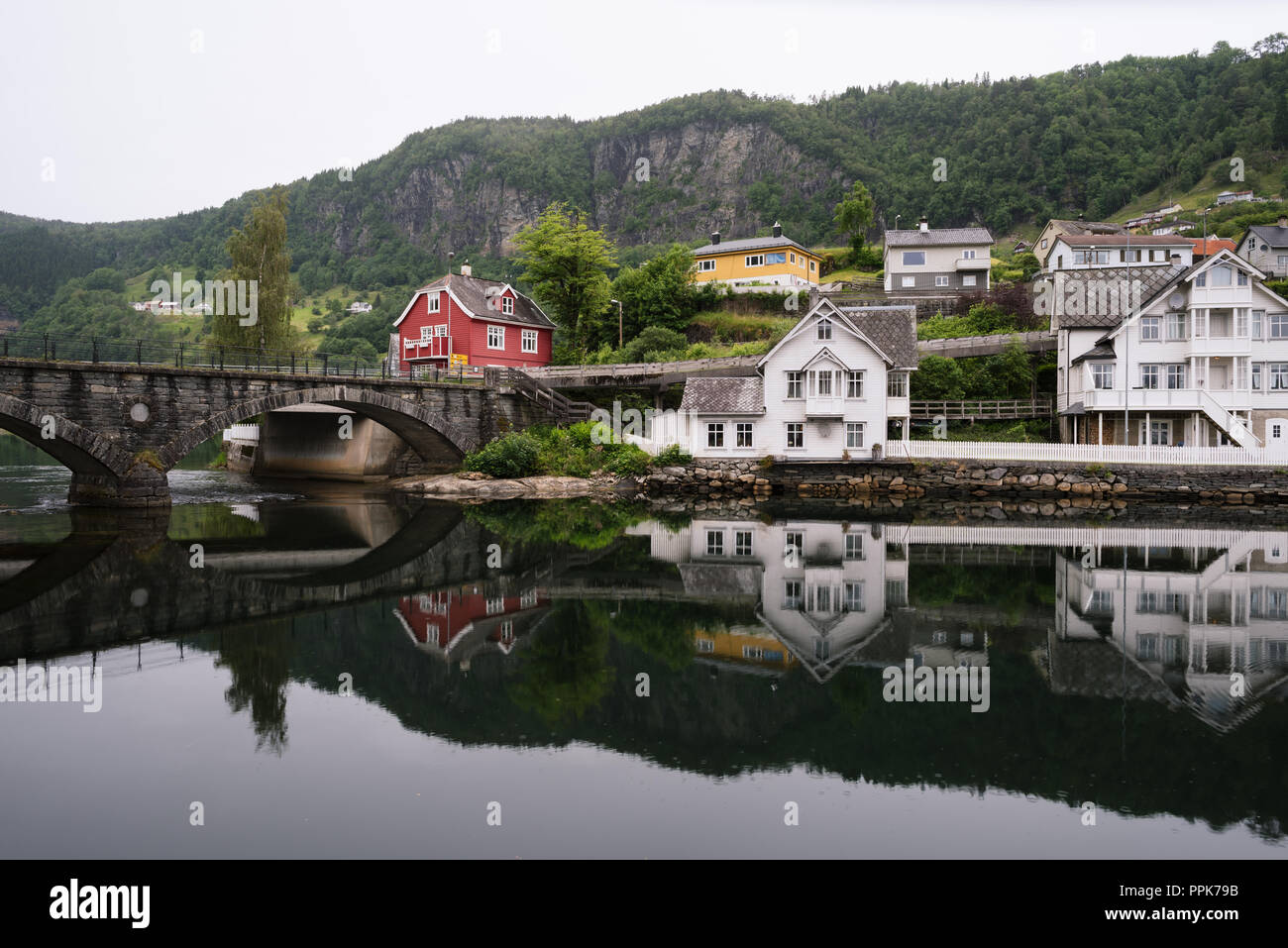 Norheimsund - norvegese città vicino al fiordo di Hardangerfjord, Norvegia. Un antico ponte in pietra. Riflessione speculare in acqua. Nuvoloso meteo settentrionale Foto Stock