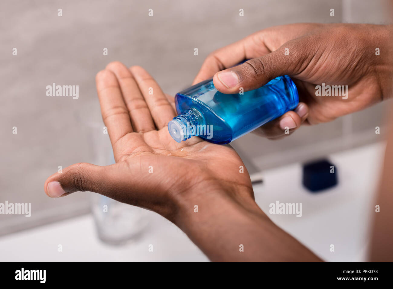 Ritagliato shot dell'uomo versando lozione dopo barba sul lato Foto Stock