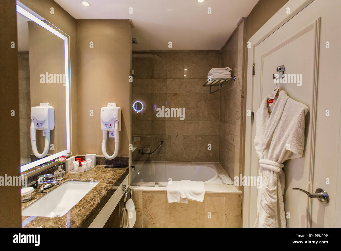 Doccia, bagno in hotel - Accessori per il bagno, asciugacapelli, specchio  sopra il lavandino e accappatoio sullo sportello, sfondo Foto stock - Alamy