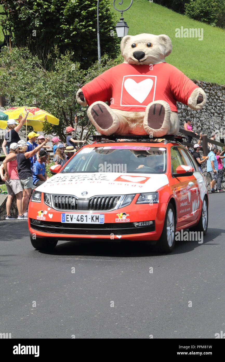 Il Mécénat Chirurgie Cardiaque vetture con il cuore bear mascot gettando regali gratuiti durante il 2018 Tour de France xvii stadio Soulan, Pirenei. Foto Stock