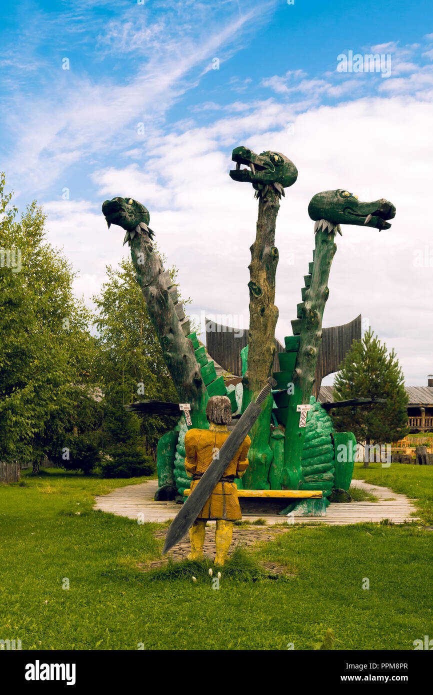 Una statua fatta di un serpente albero con tre teste e un guerriero con una sciabola dietro le sue spalle Foto Stock