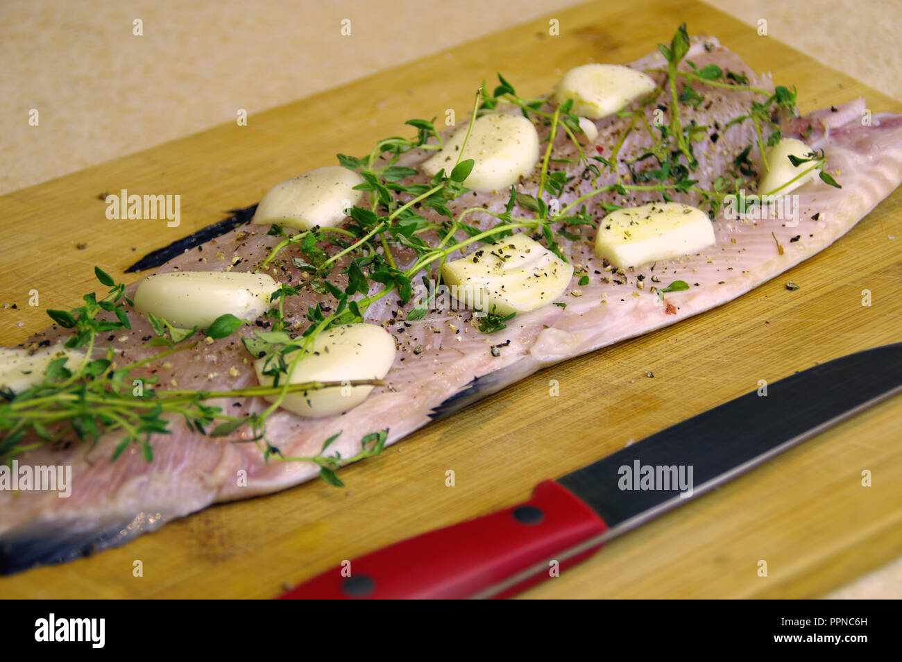 Fresco pesce crudo pronto per la cottura. Trota con erbe aromatiche, aglio e spezie su una tavola di legno Foto Stock