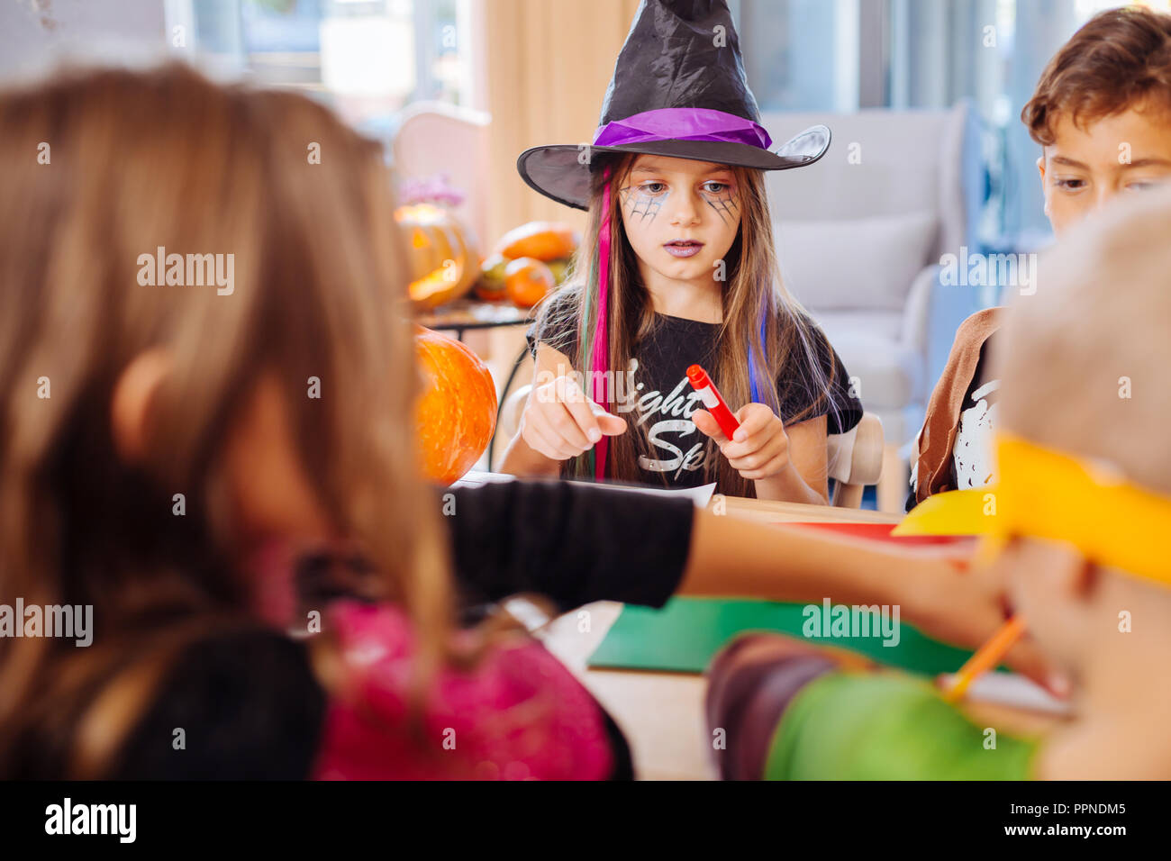 Ragazza dai capelli scuri che indossa la procedura guidata black hat per la festa di Halloween a giocare con gli amici Foto Stock