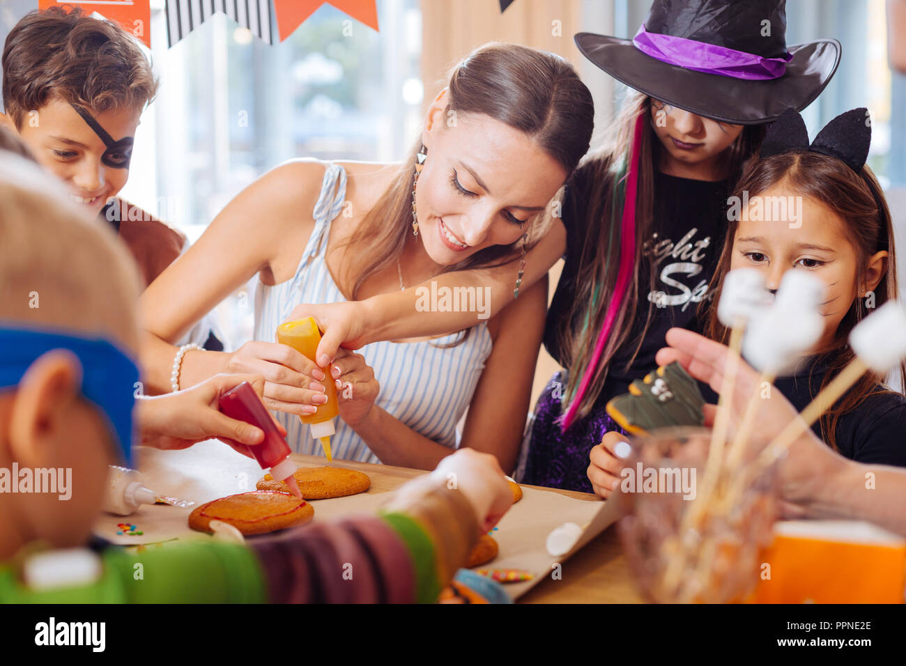 Amorevole Madre sorridente aiutando i suoi figli rendendo i cookie per Halloween Foto Stock