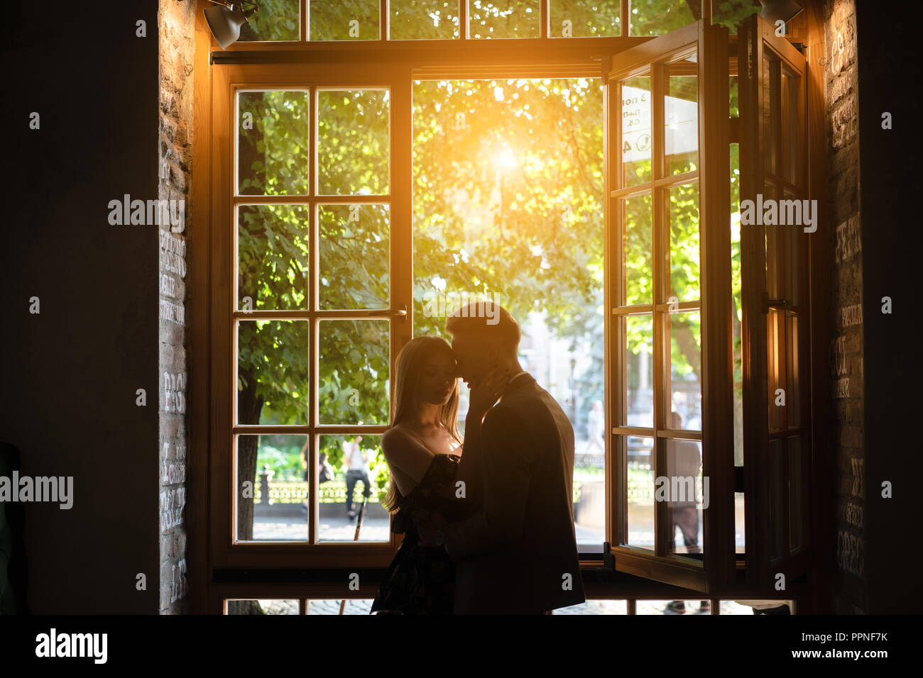 Coppia giovane in amore in piedi dalla finestra Foto Stock