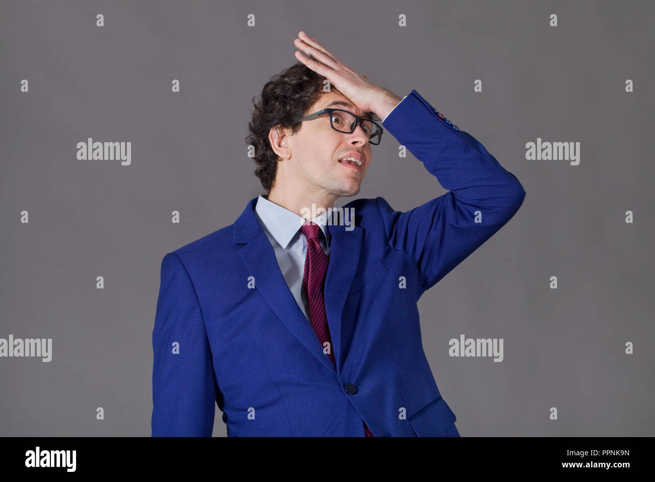 Ragazzo con i capelli ricci e giacca blu dimenticare di qualcosa di importante Foto Stock