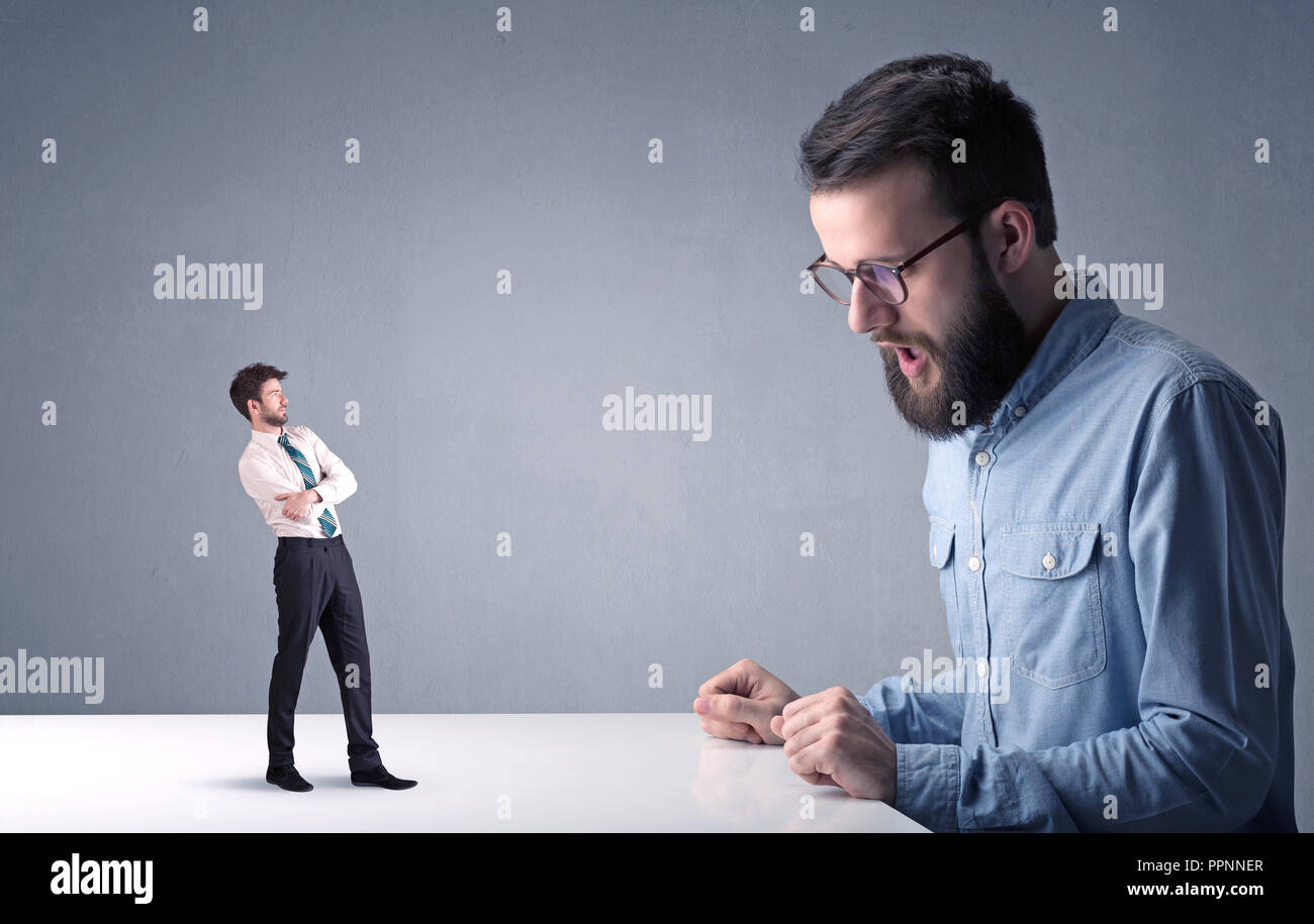 Giovane imprenditore professionale essendo arrabbiato con un altro imprenditore in miniatura Foto Stock