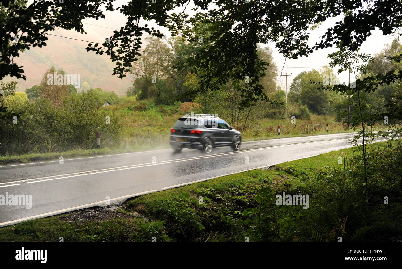 Automobile che viaggia vicino a Glencoe Scozia ri flette in strada la guida delle Highlands ubicazioni remote strade bagnate SCOTTISH REGNO UNITO Foto Stock