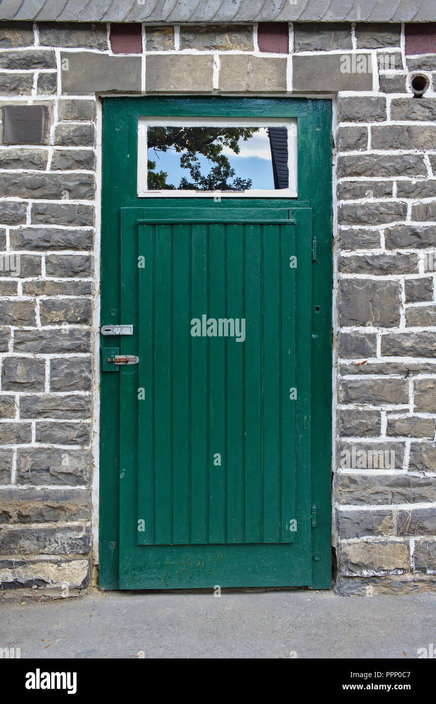 Grigio a muro di pietra verde con porta di legno Foto Stock