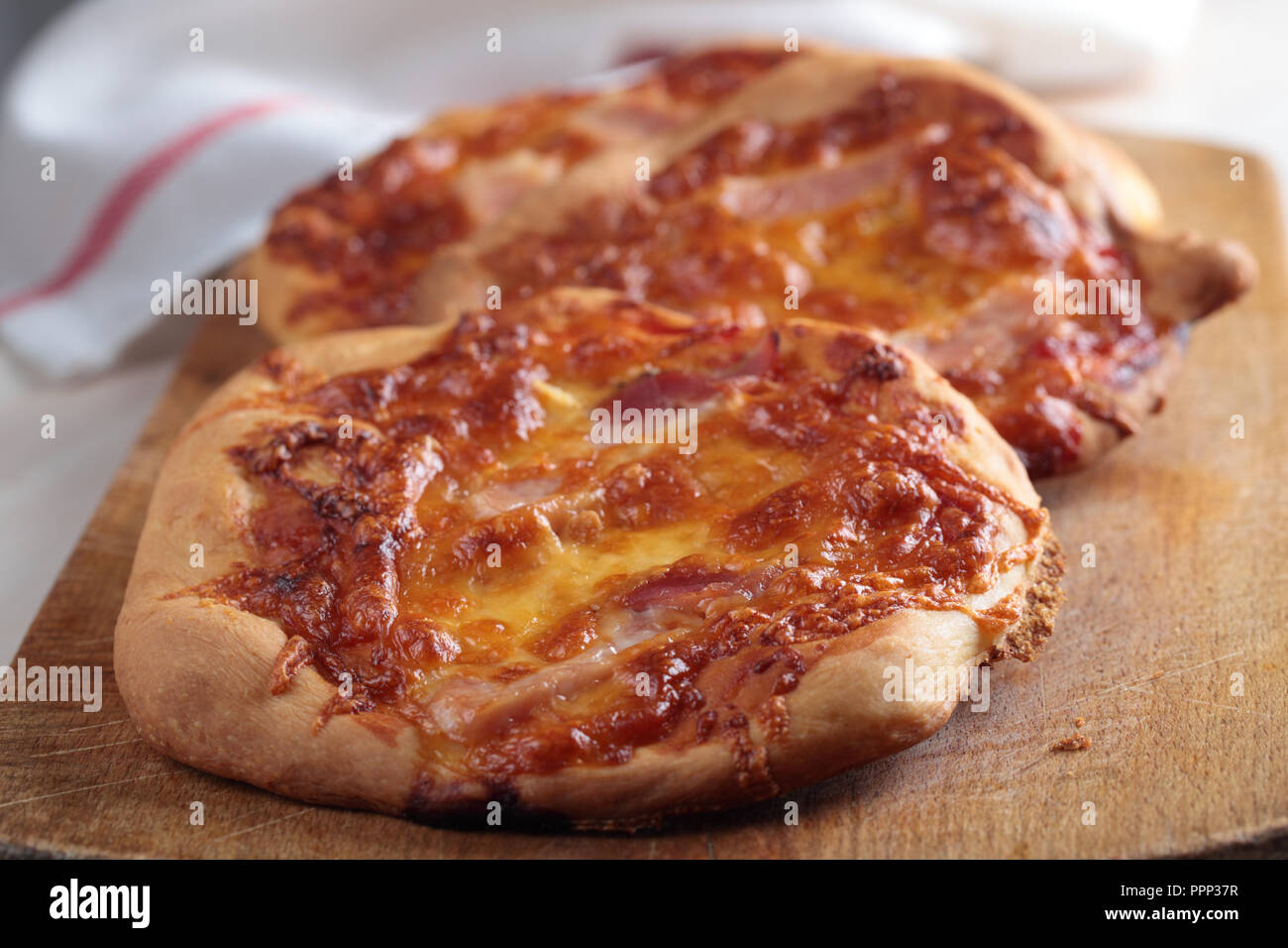 Le pizze fatte in casa con mozzarella e salsa di pomodoro su un tagliere di legno Foto Stock