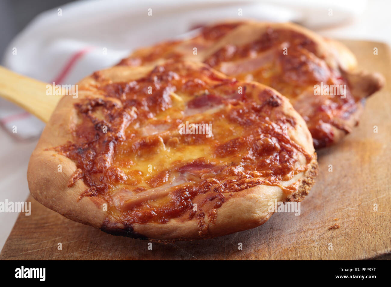 Le pizze fatte in casa con mozzarella e salsa di pomodoro su un tagliere di legno Foto Stock