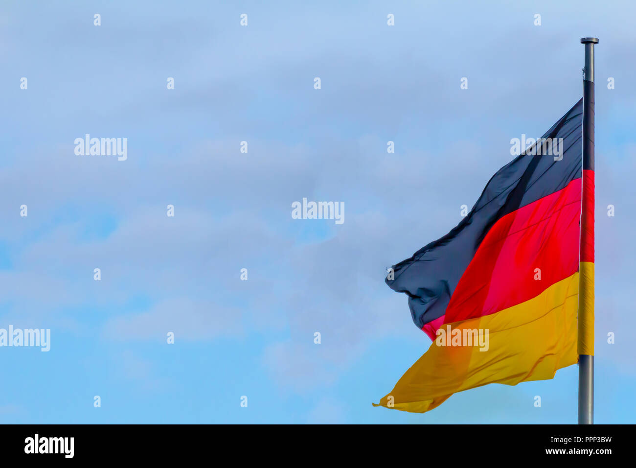 Repubblica federale di Germania, nazionale tedesco di bandiera sventola sul cielo blu sullo sfondo Foto Stock