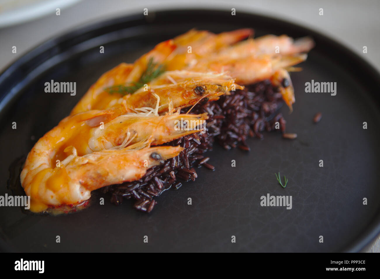 Gamberoni in riso nero sulla piastra nera Foto Stock