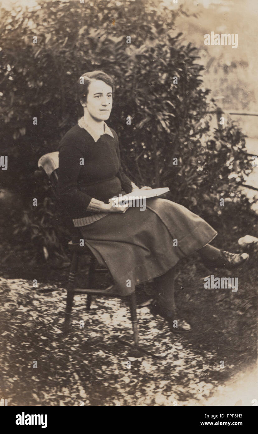 Vintage fotografia di una Signora Sat all'aperto la lettura di un libro Foto Stock