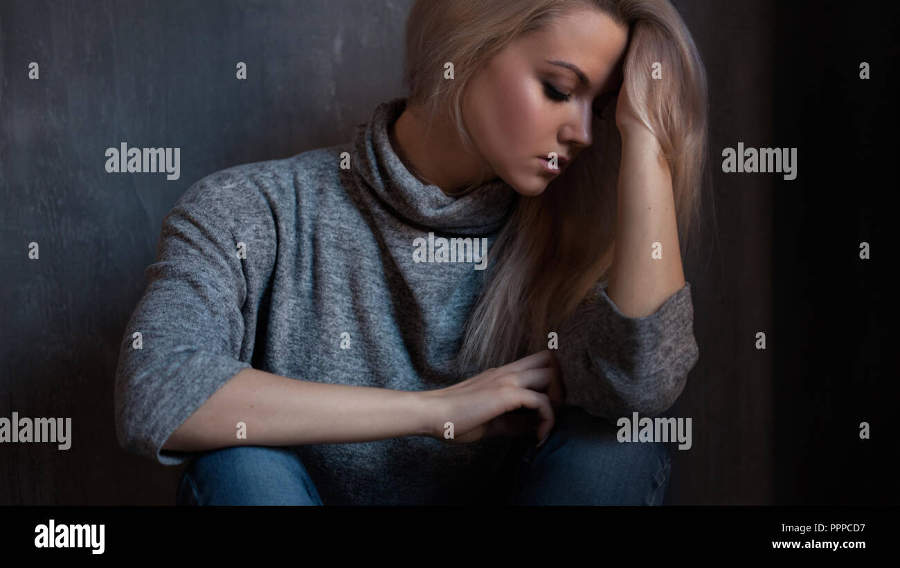 Premuto donna. ragazza bionda seduta sul pavimento, la tristezza e la depressione, la nozione di problema psicologico Foto Stock