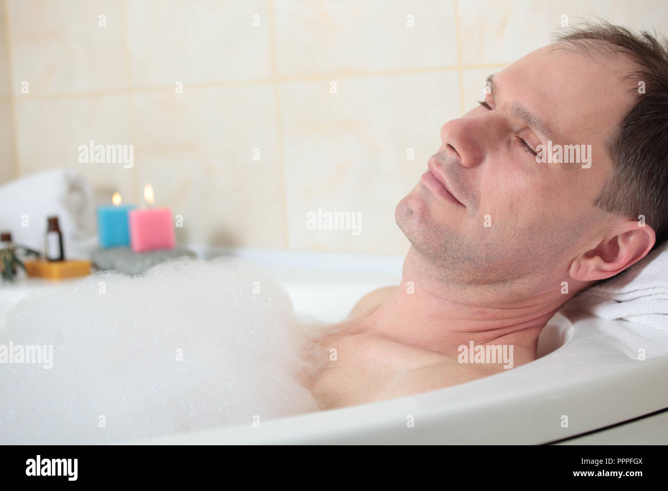 Uomo adulto avente una vasca da bagno con olio essenziale Foto Stock
