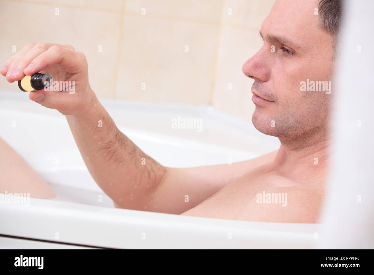 Uomo adulto avente una vasca da bagno con olio essenziale Foto Stock
