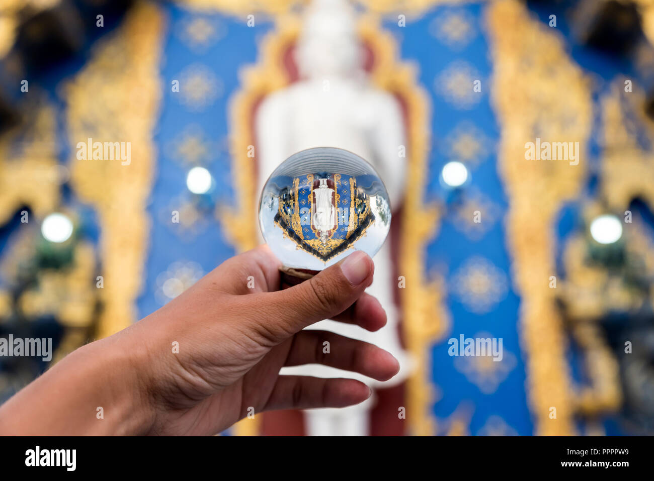 Il raccolto di mano azienda turistica sfera di vetro con upside riflessione di antico tempio in Thailandia Foto Stock
