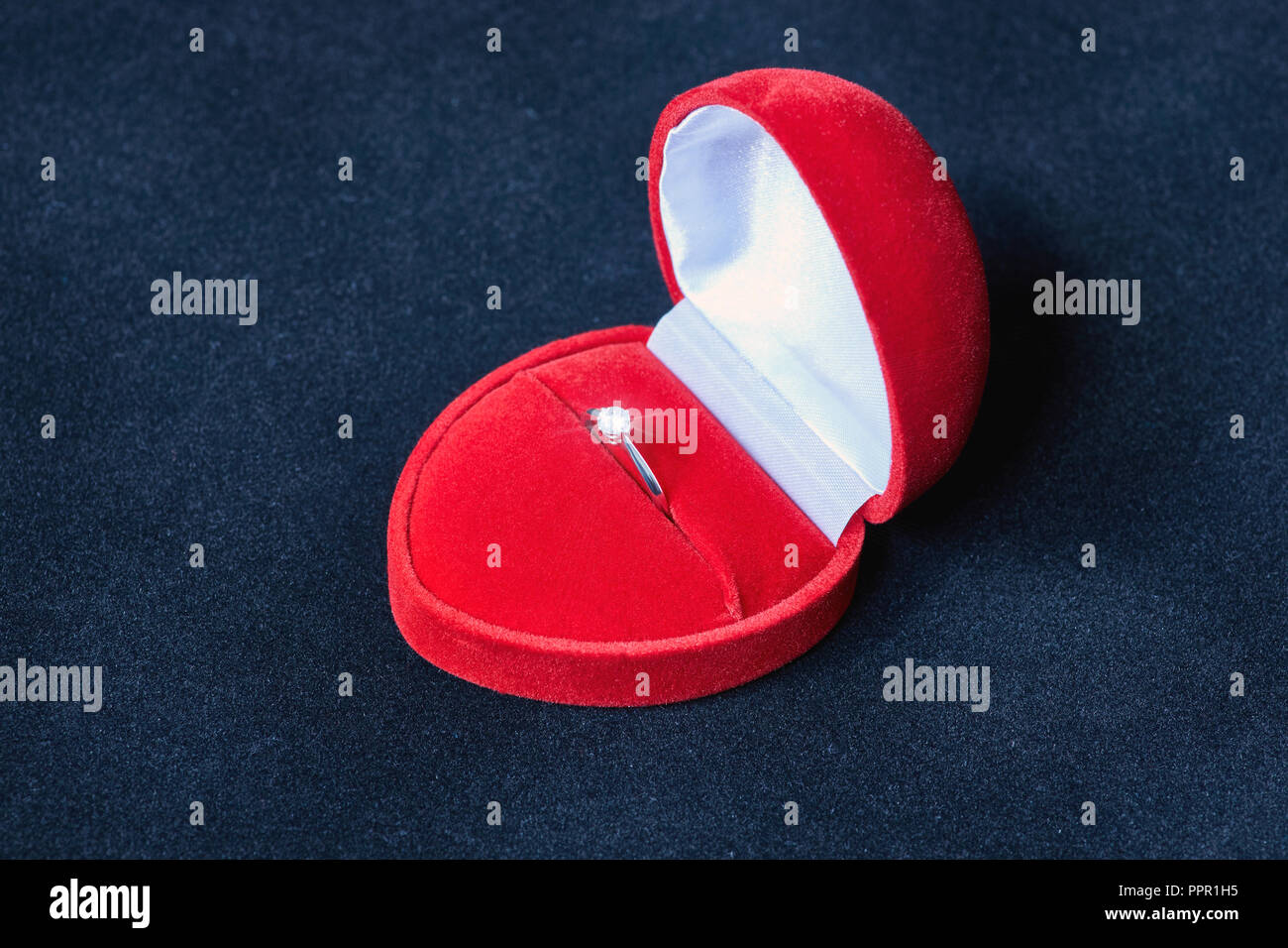 Un impegno anello di argento in una casella rossa a forma di cuore con un brillante pietra preziosa Foto Stock