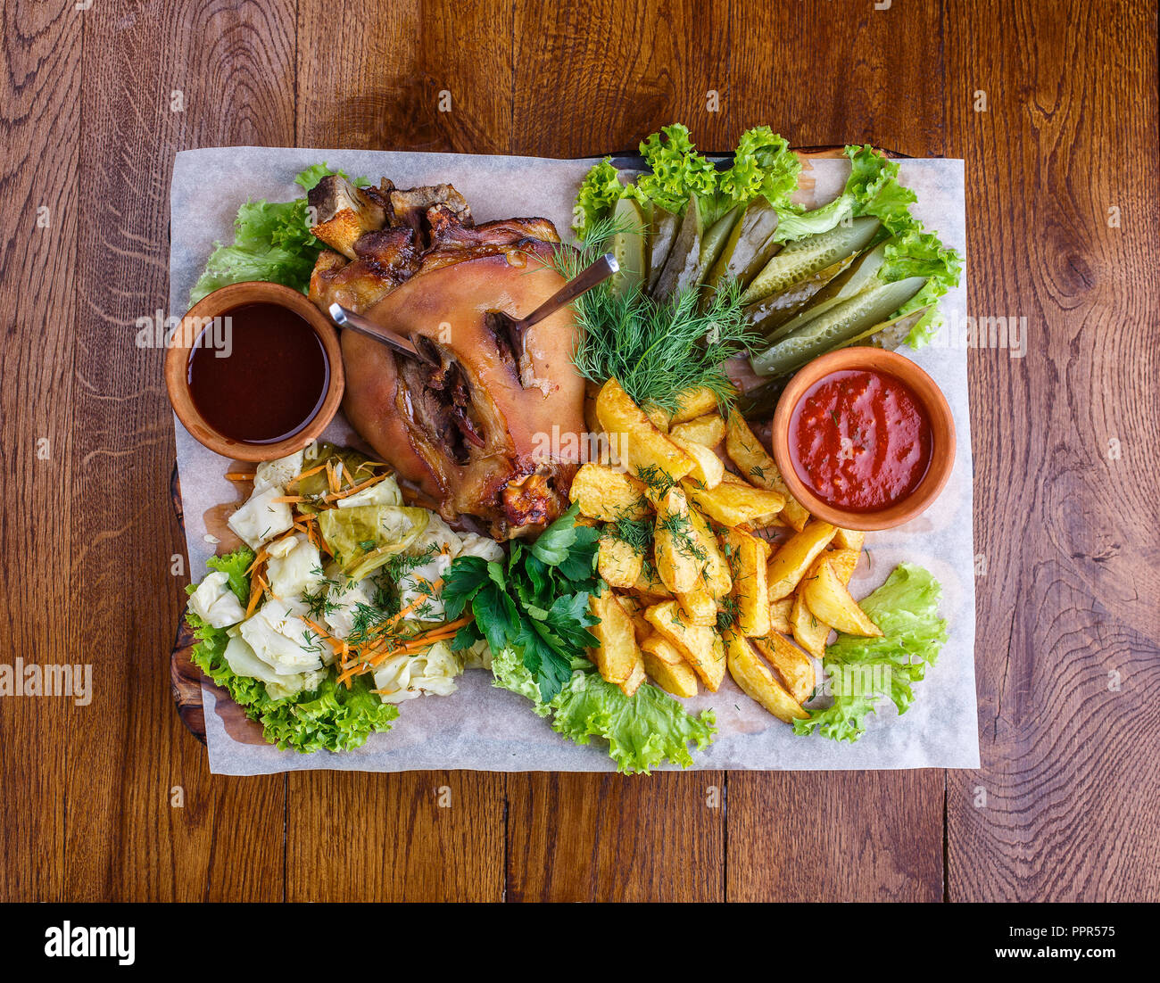 Spuntini per la birra al pub. Carne di maiale affumicato gamba con patate, cetrioli sottaceto, cavolo, prezzemolo, insalata, aneto e salsa rossa. Foto da sopra Foto Stock