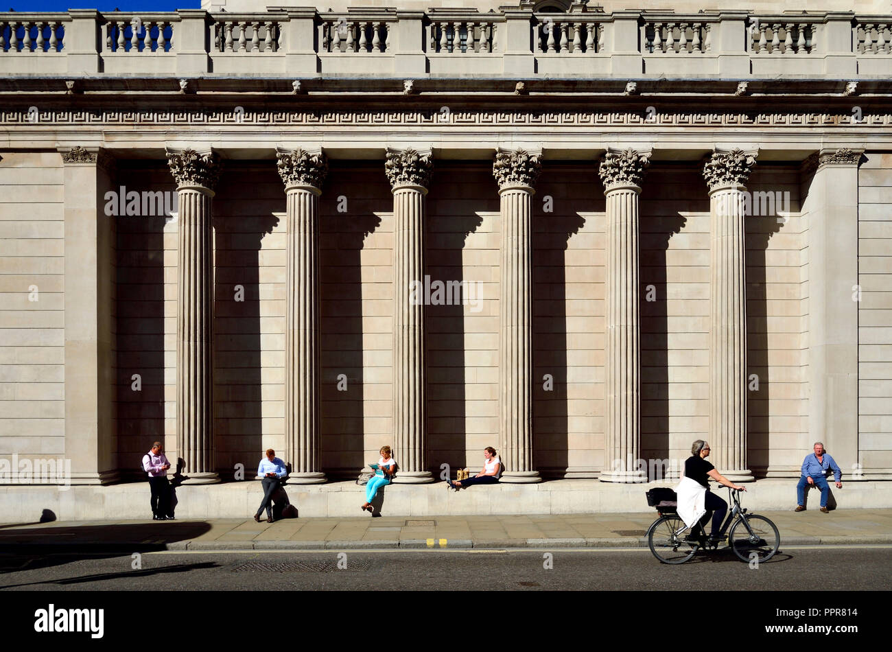 La gente seduta sulla facciata meridionale della Bank of England, Londra, Inghilterra, Regno Unito. Foto Stock