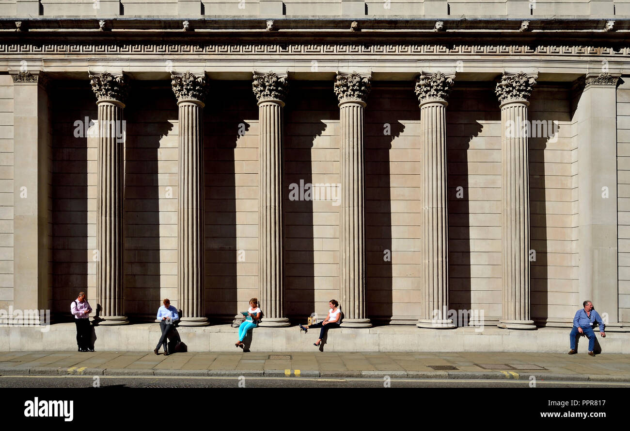 La gente seduta sulla facciata meridionale della Bank of England, Londra, Inghilterra, Regno Unito. Foto Stock