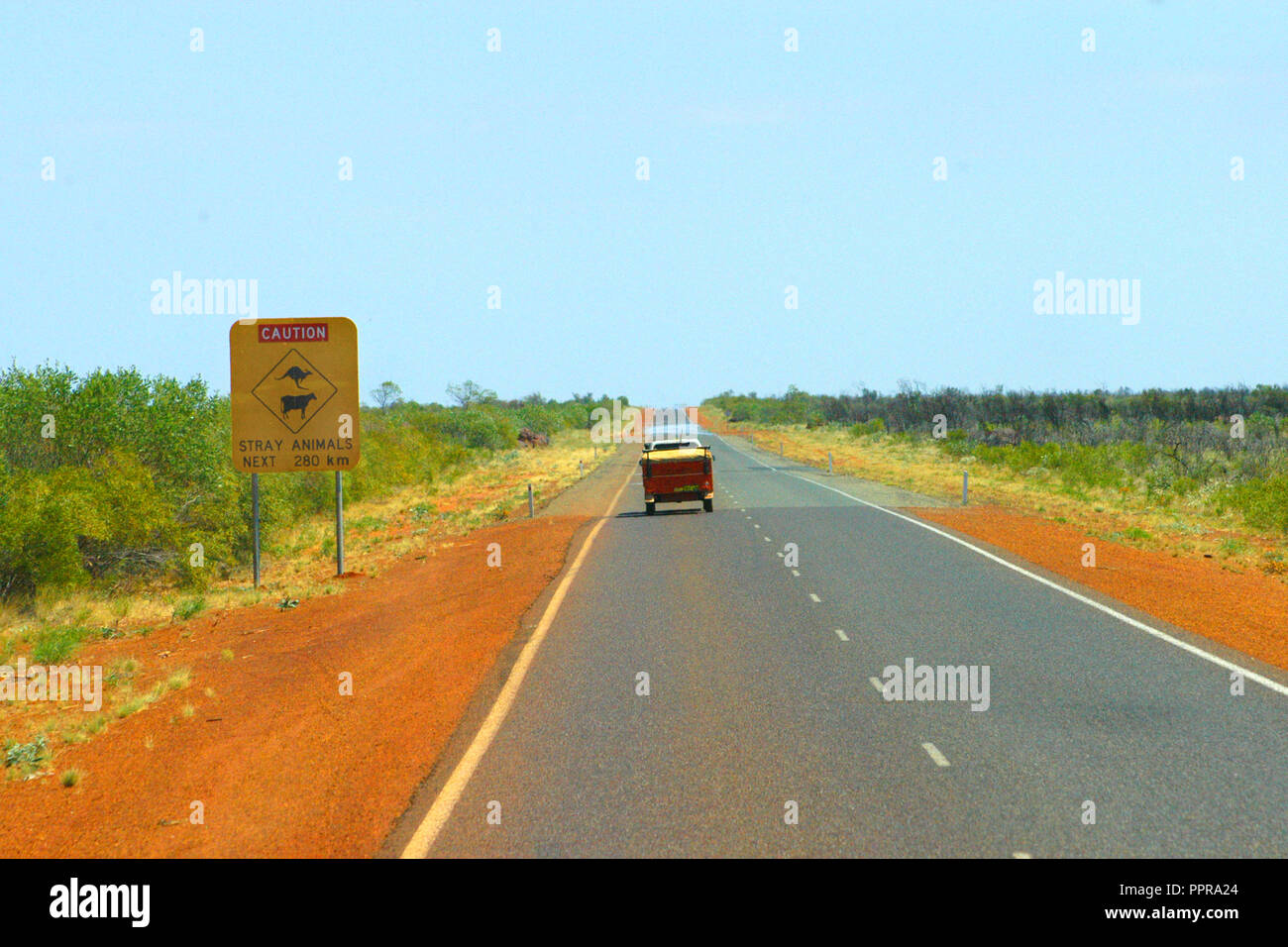 Un veicolo su un outback strada passa un gli animali randagi cartello stradale, outback Australia Occidentale Foto Stock