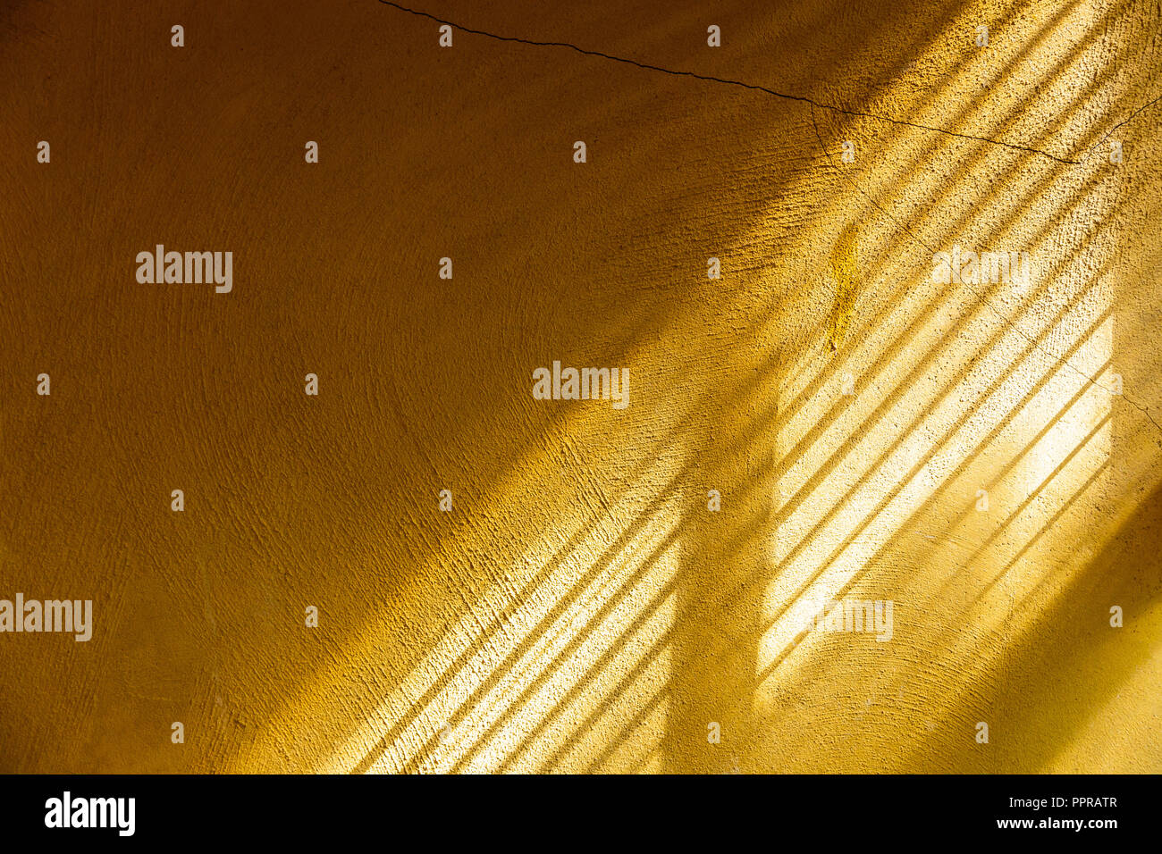 Il giallo muro di cemento di toccare la luce solare attraverso la finestra per mostrare la superficie della parete ruvida e rendendo la separazione di parti di luce e di ombra. Foto Stock