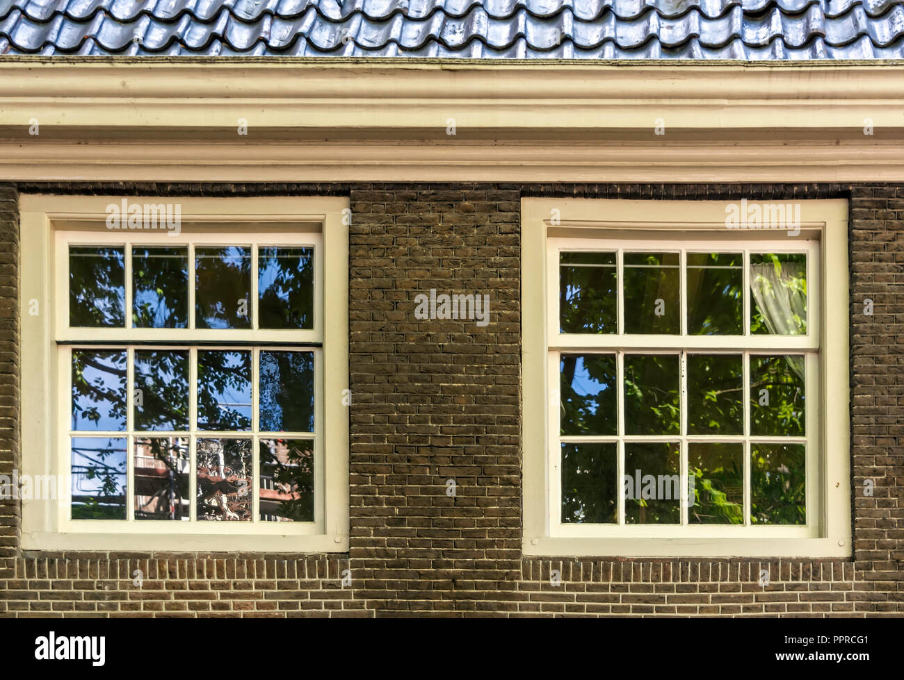 Due bianchi vintage finestre a ghigliottina in marrone e parete di mattoni. Edificio retrò in Amsterdam, Paesi Bassi, elementi architettonici. Foto Stock