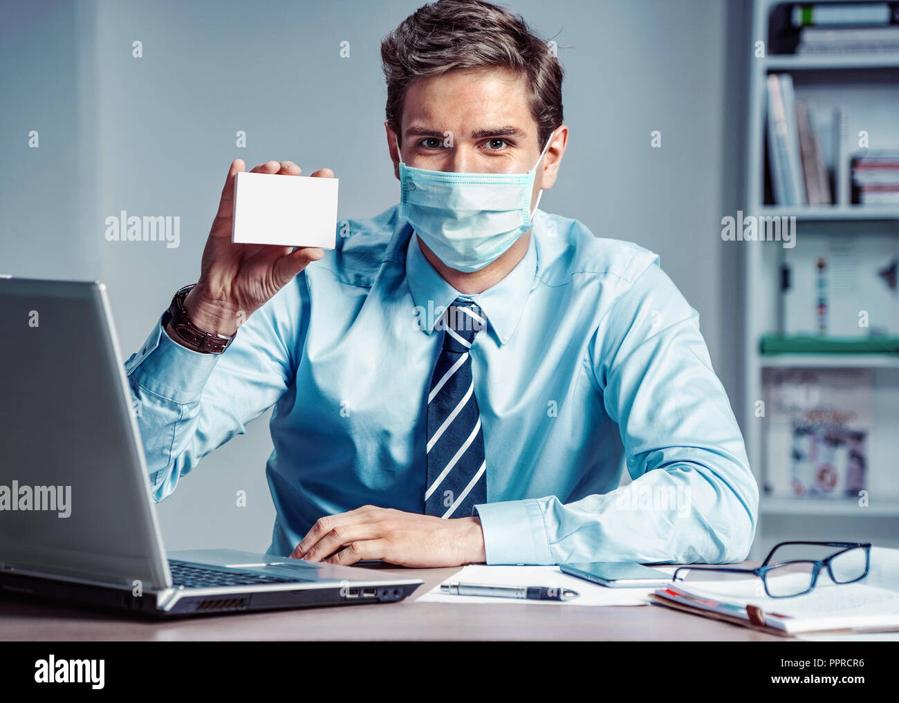 Lavoratore sano in ufficio azienda casella bianca della medicina. Foto di un uomo che indossa la maschera di protezione contro le malattie infettive e l'influenza. Business e hea Foto Stock