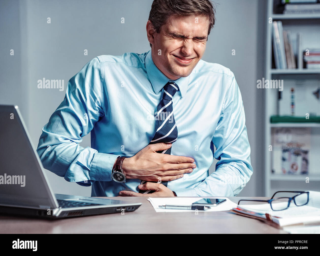 Dipendente soffre di dolori di stomaco. Foto di un uomo lavora in ufficio. Concetto medico. Foto Stock