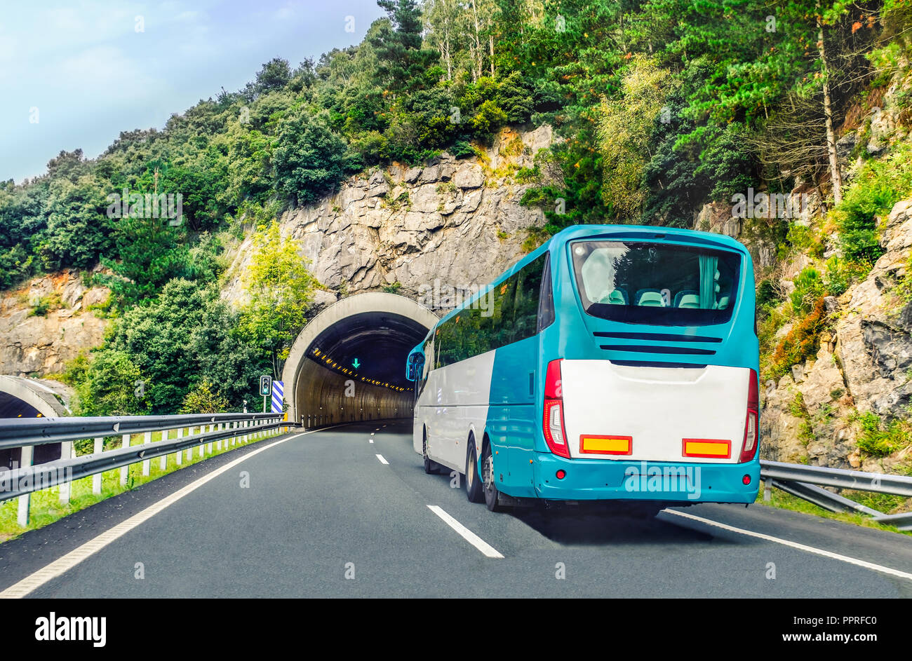 Un bianco e blu, pullman o long haul bus per turisti aziona attraverso il tunnel di montagna e strade del nord della Spagna, Europa in un giorno d'estate. Foto Stock
