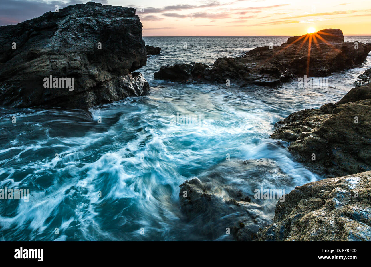 Un roccioso e aspro paesaggio costiero con il bianco delle onde che si infrangono sulla battigia e che scorre contro rocce dure in Cornwall, Regno Unito Foto Stock