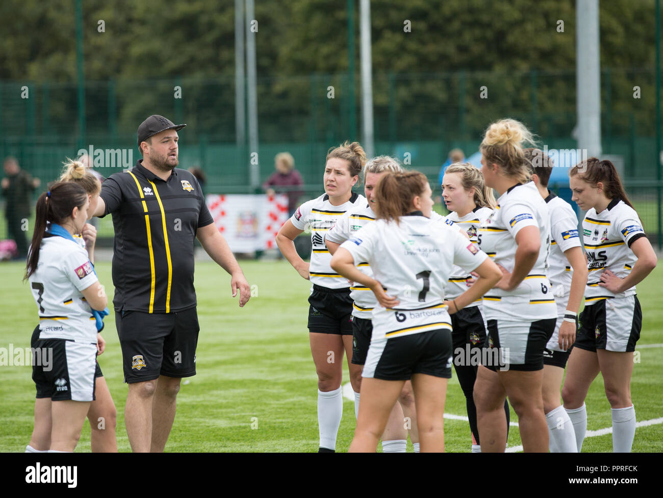 Un gruppo di donne del rugby giocatori ascoltando loro pullman parlare le tattiche di squadra durante una pausa di metà tempo a una partita di rugby. Foto Stock