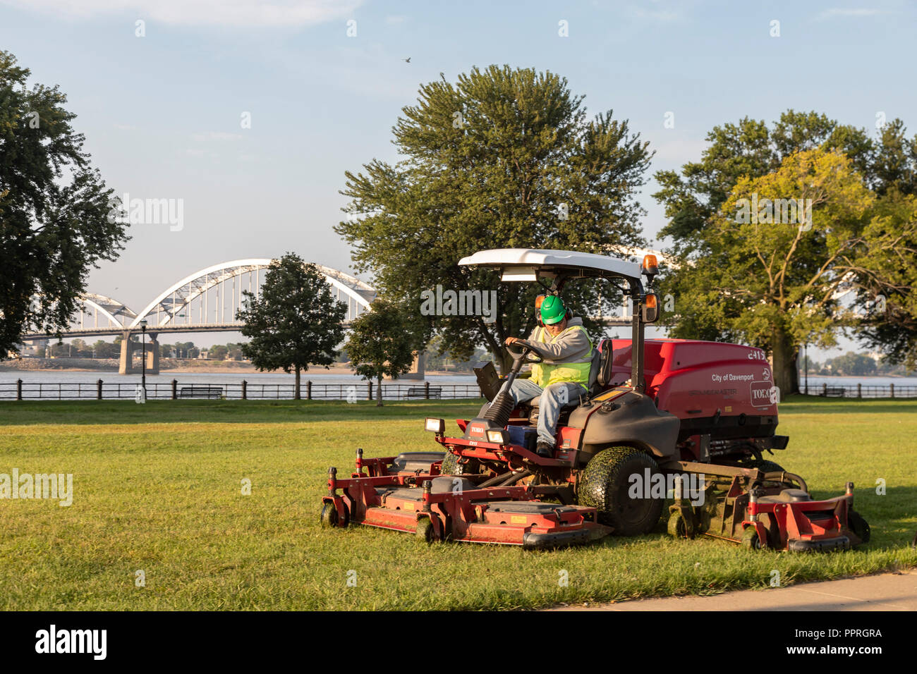 Davenport, Iowa - una città dipendente taglia l'erba in LeClaire parco lungo il fiume Mississippi. Foto Stock